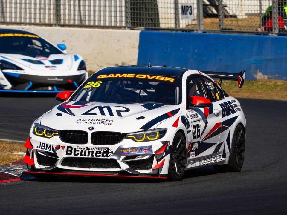 A BMW M4 GT4 race car at speed through a corner.