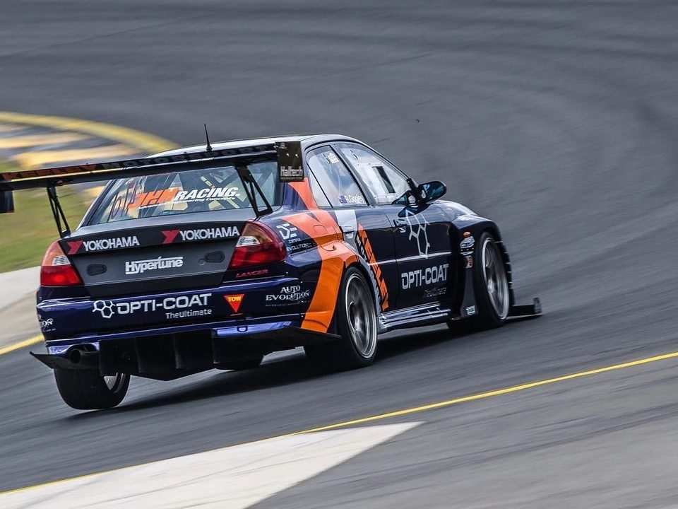 A time attack Evo with a large rear wing powering out of a corner.
